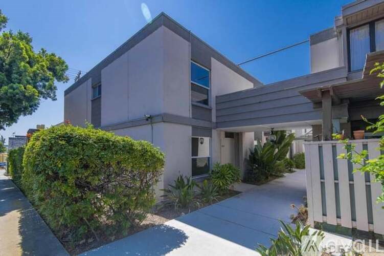 A modern house with a white picket fence in front.