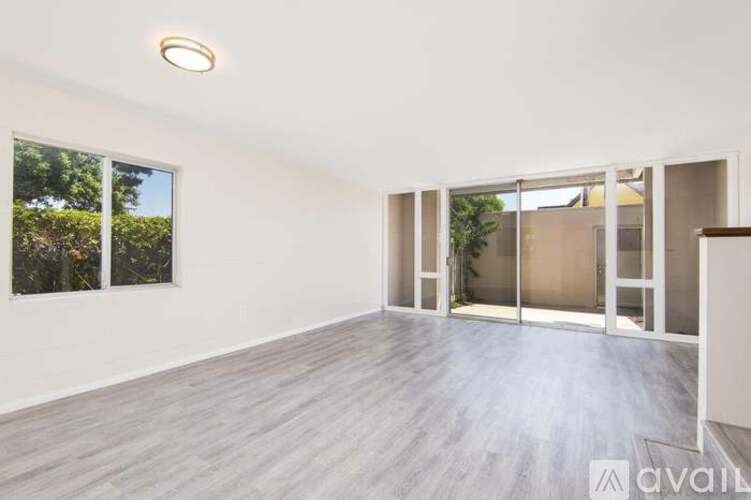 A spacious room with wooden flooring and large windows.