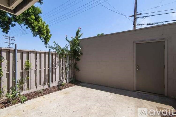 A concrete wall with a door and a fence with green plants on it.