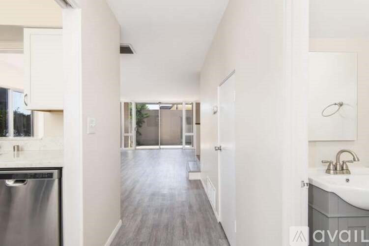 A long, narrow hallway with a sink on the right and a door at the end.