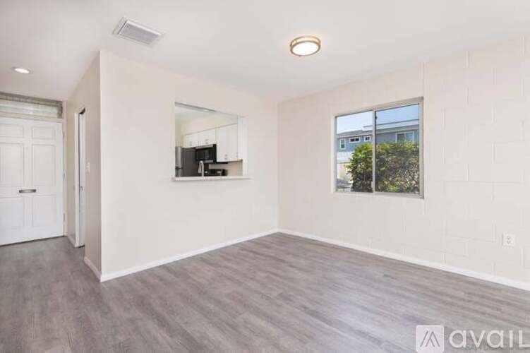 A spacious room with a kitchenette and a window overlooking a tree.