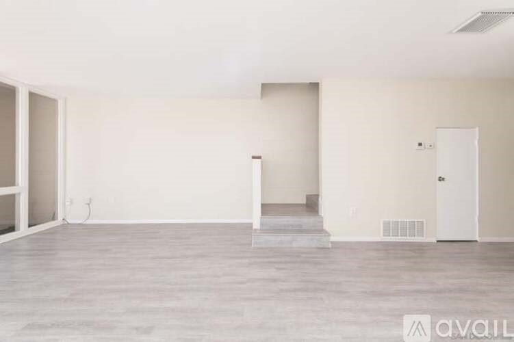 A spacious room with a door in the middle and a window on the left.