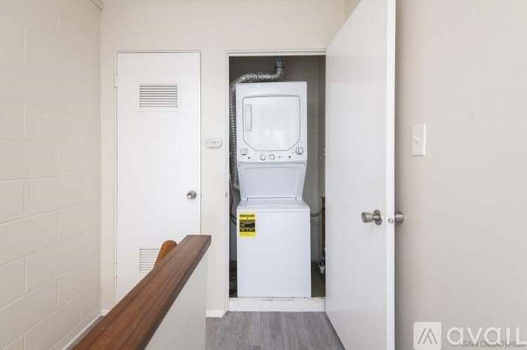 A small white fridge in a narrow hallway.