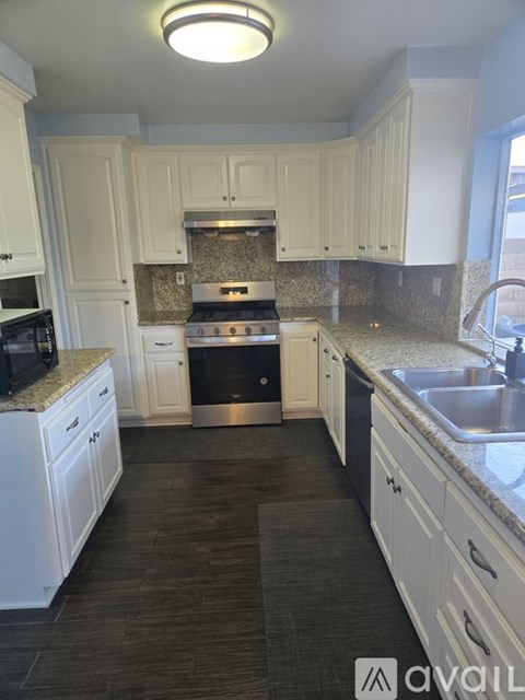 A kitchen with white cabinets and a black floor.