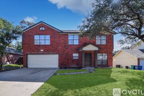 A red brick house with a white garage door and a tree in front.