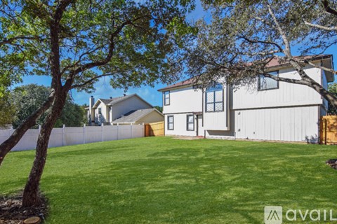 A house with a white exterior and a large tree in front of it.