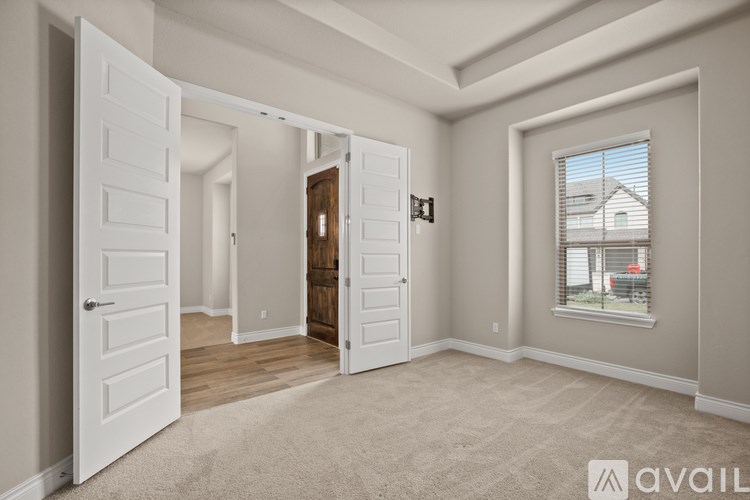 A room with a carpeted floor and a window showing a house outside.