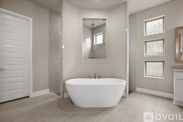 A white bathroom with a tub and a mirror.