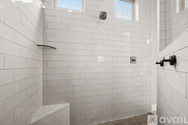 A bathroom with white tiles and a window.