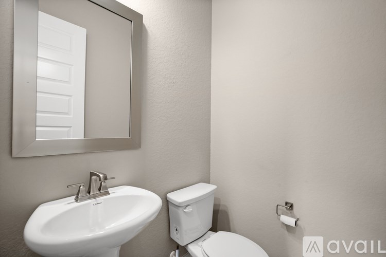 A bathroom with a toilet, sink, and mirror.