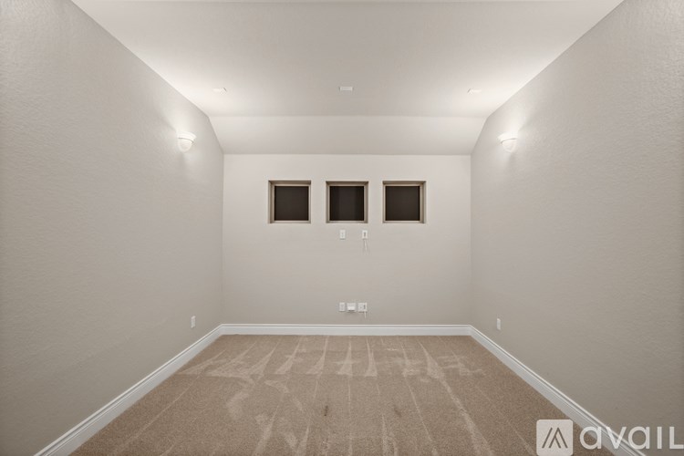 A room with a carpeted floor and two windows.