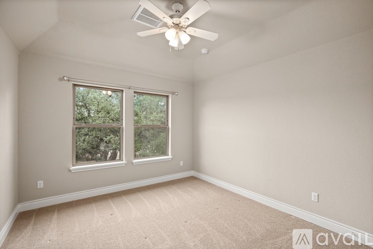 A room with a ceiling fan and two windows.