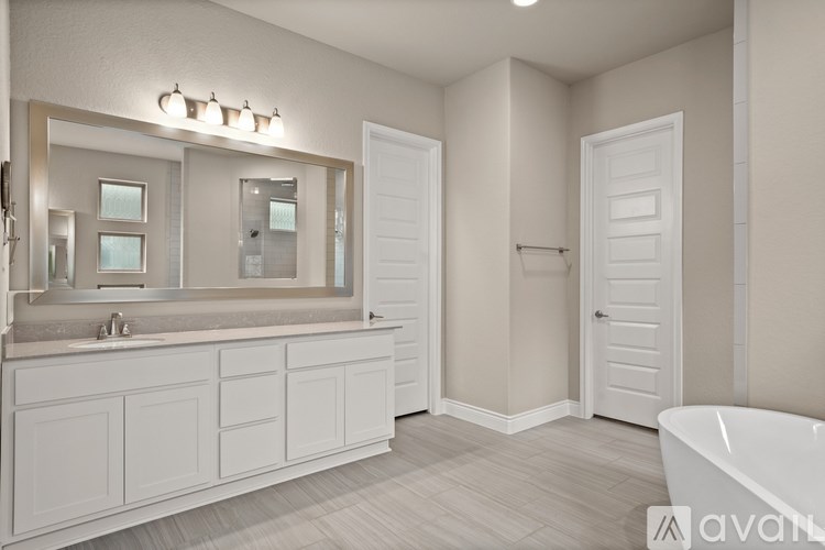 A white bathroom with a large mirror and a bathtub.