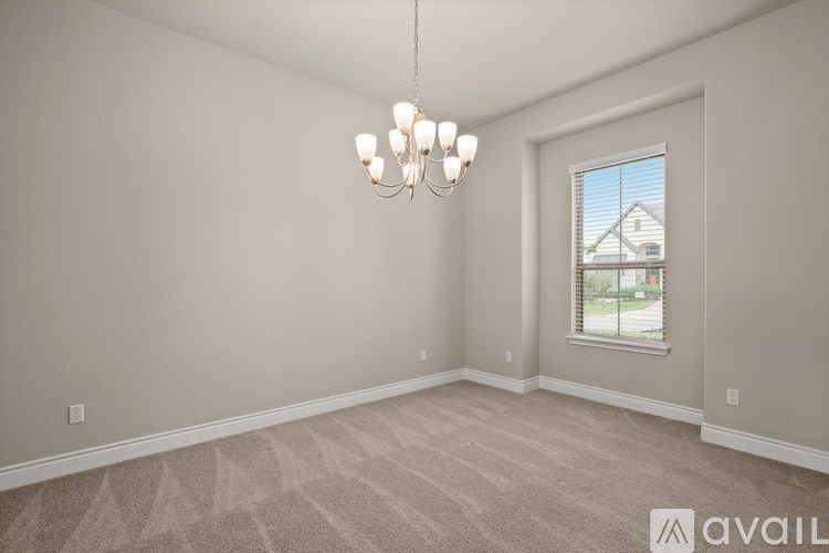 A room with a chandelier and a window with blinds.