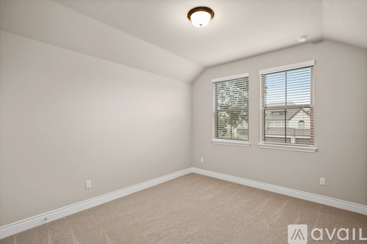 A room with a carpeted floor and two windows.