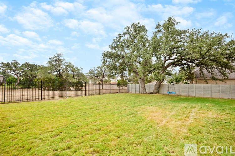 A grassy field with a fence and trees in the background.