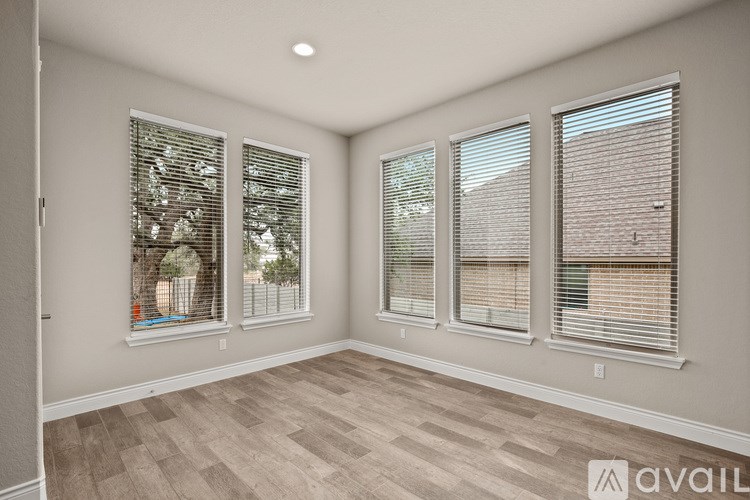 A room with three windows and wooden flooring.