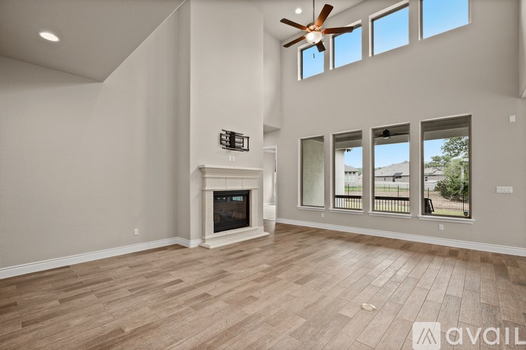 A spacious living room with a fireplace and a ceiling fan.