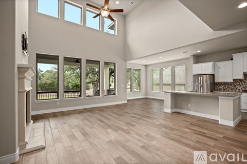 A spacious kitchen and living room with hardwood floors and a ceiling fan.