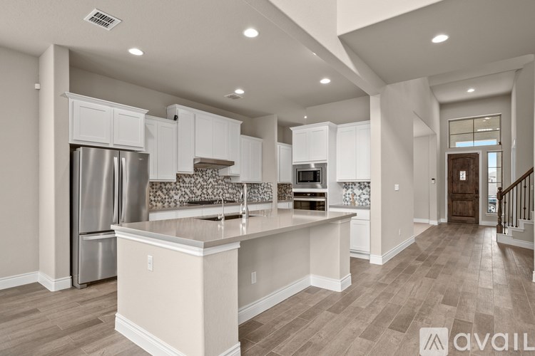 A kitchen with a refrigerator, sink, and cabinets.