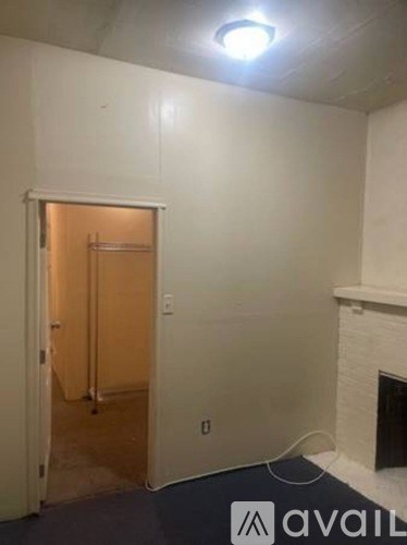 A room with a fireplace and a doorway leading to another room.