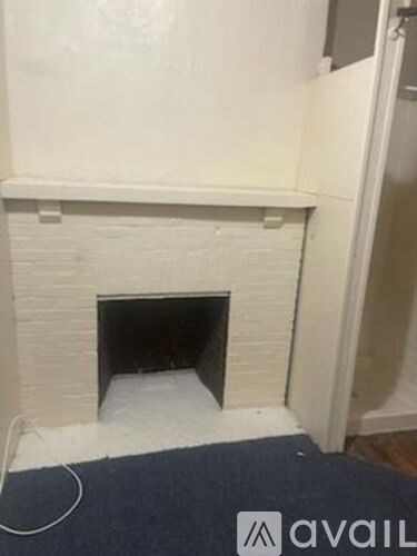A white brick fireplace with a black fire grate in the middle.