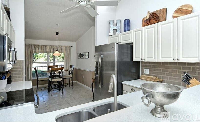 A kitchen with a black refrigerator and a dining table with chairs.
