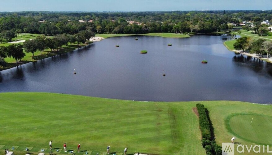 A golf course with a lake and a group of people playing golf.