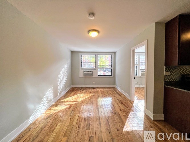 A room with wooden floors and a window with a view of a building.