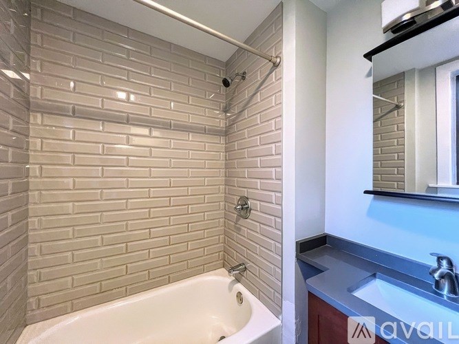 A white bathtub sits in a bathroom with a brick wall behind it.