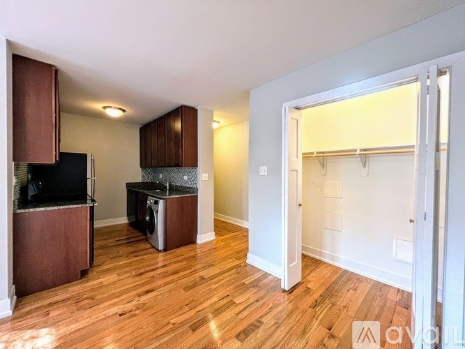A kitchen area with wooden floors and a black fridge.
