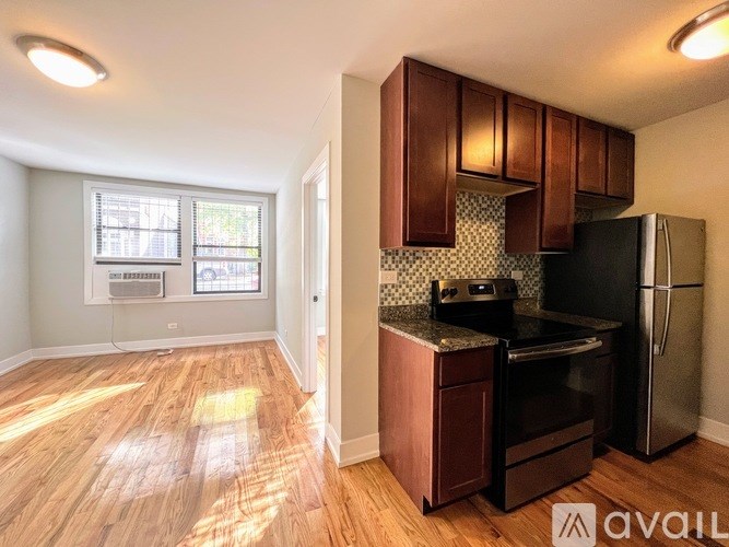 A kitchen with wooden floors and a black refrigerator.
