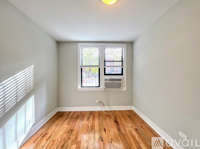 A room with wooden flooring and a window with blinds.