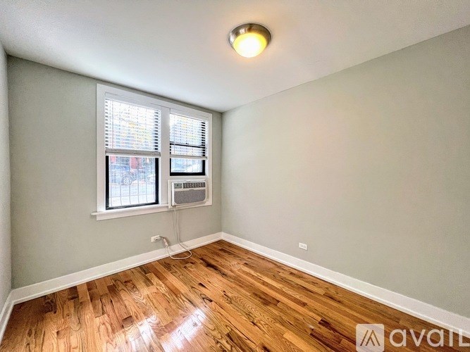 A room with wooden flooring and a window with blinds.