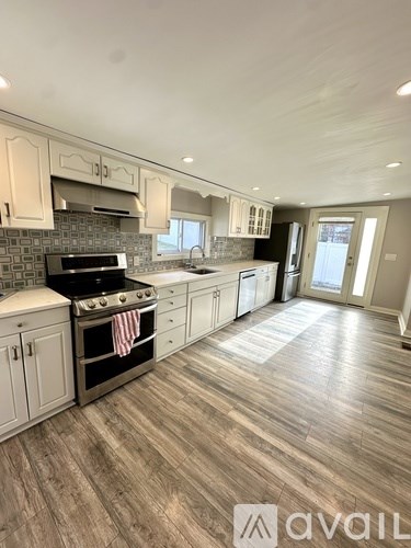 A kitchen with wooden floors and white cabinets.