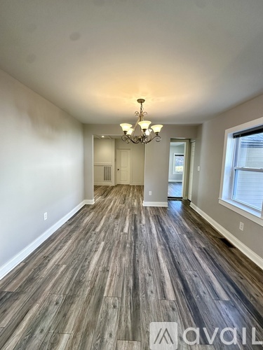 A room with wooden flooring and a chandelier.