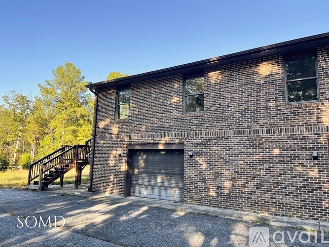A brick building with a garage door and a staircase leading to the entrance.