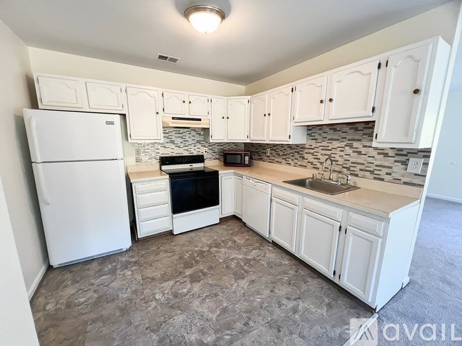 A kitchen with white cabinets and a white fridge.