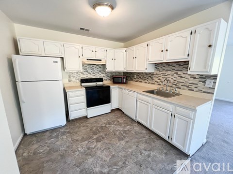 A kitchen with white cabinets and a white fridge.