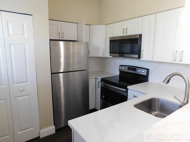 A kitchen with white cabinets and a stainless steel refrigerator.