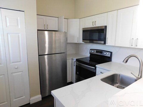 A kitchen with white cabinets and a stainless steel refrigerator.