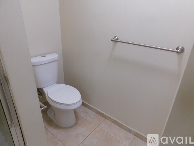 A white toilet in a small bathroom with a grab bar.