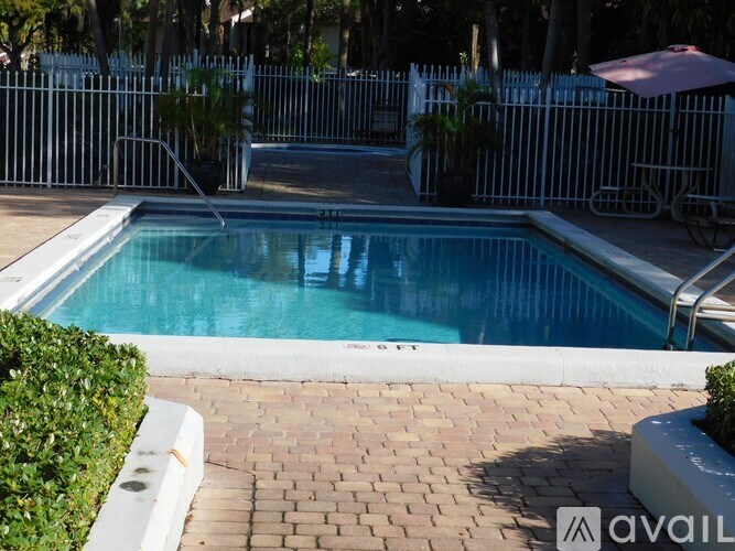A pool surrounded by a white fence and a brick walkway.