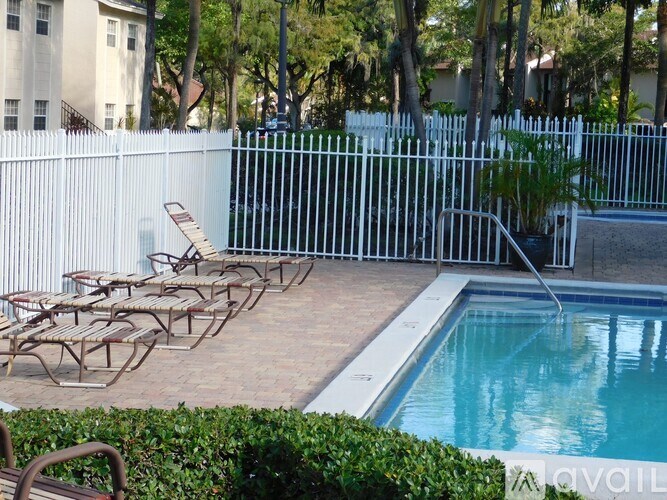 A pool surrounded by a white fence and chairs.