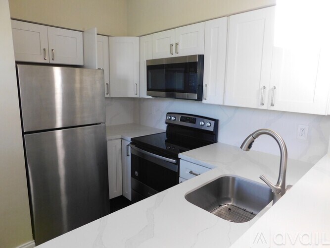 A kitchen with a stainless steel refrigerator, microwave, oven, and sink.