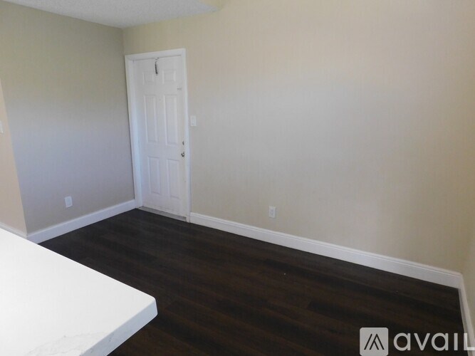 A room with a white door and wooden floor.