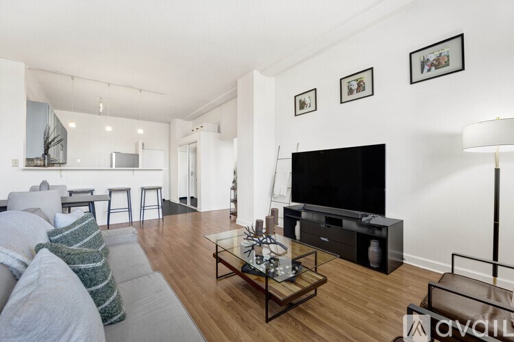 A living room with a grey couch, a coffee table, a flat screen TV, and a bar area.