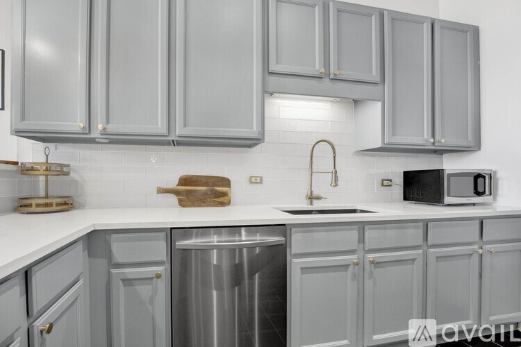 A kitchen with grey cabinets and a stainless steel dishwasher.