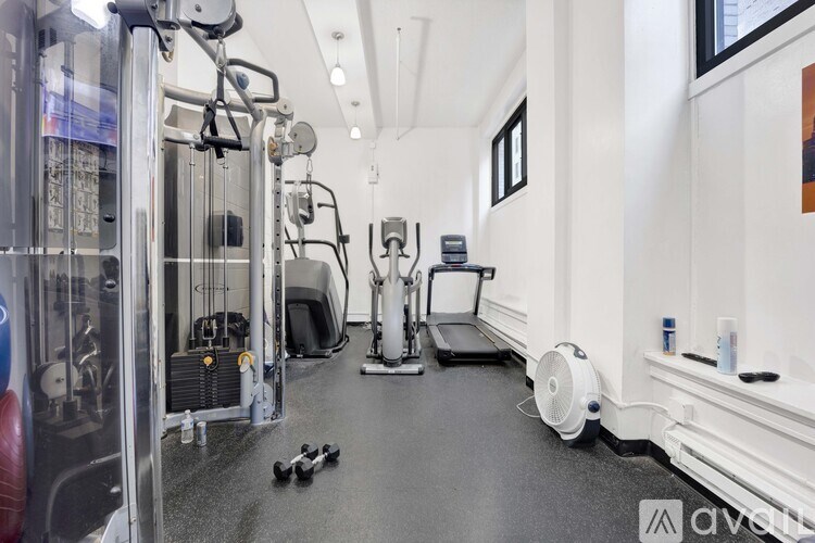 A gym with a variety of equipment including a treadmill, weights, and a fan.