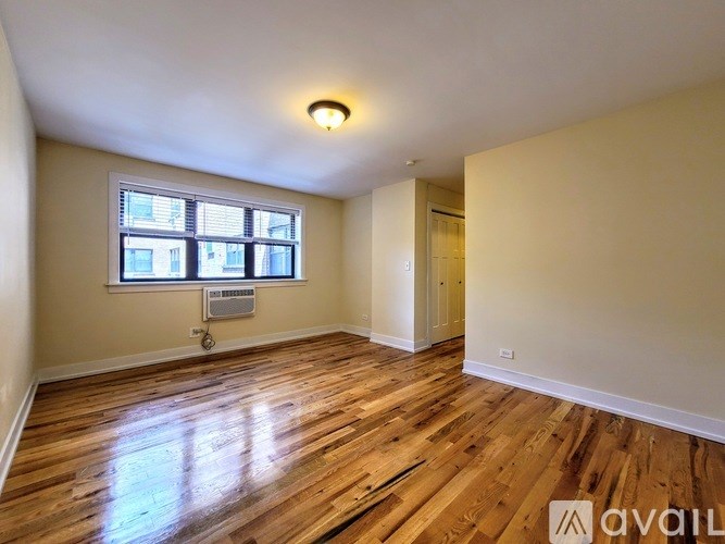 A room with wooden floors and a window with blinds.